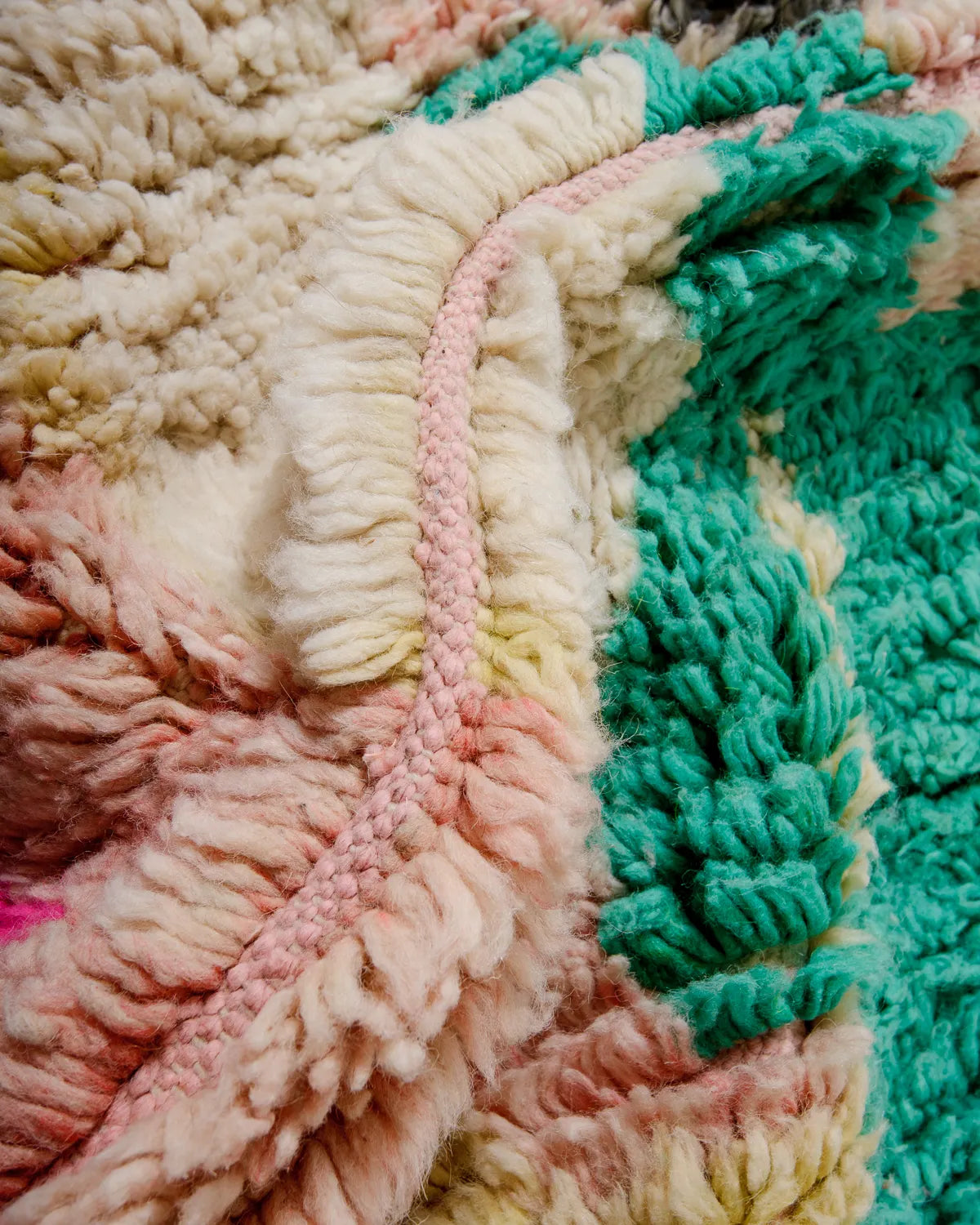 Detail of vintage Berber rug from Morocco featuring fluffy wool in shades of cream, pink, peach, yellow and turquoise.